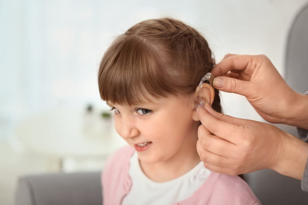 Young girls receiving a hearing aid