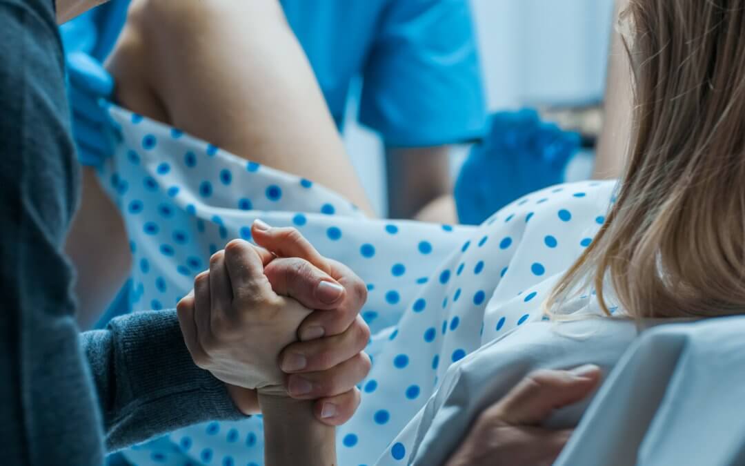 Woman in labour holding her partner's hand