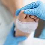 Close up of a bandaged foot being examined by a doctor.