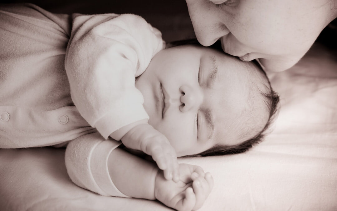 sleeping-newborn-baby-closeup-face-with-mother-kissing