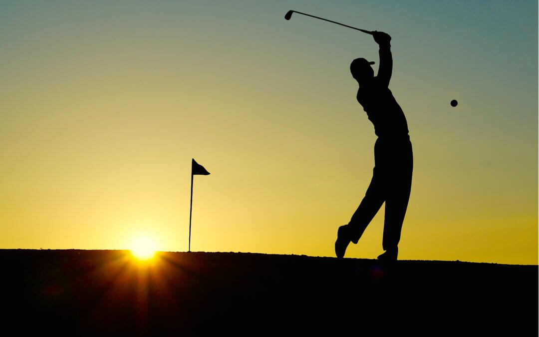 Silhouette of man playing golf in the sunset