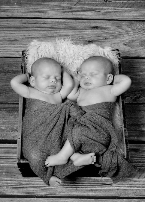 Black and white photo of twins sleeping in a crib together