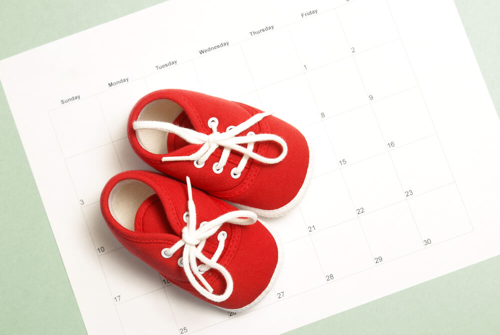 A pair of red baby shoes on top of a weekly calendar