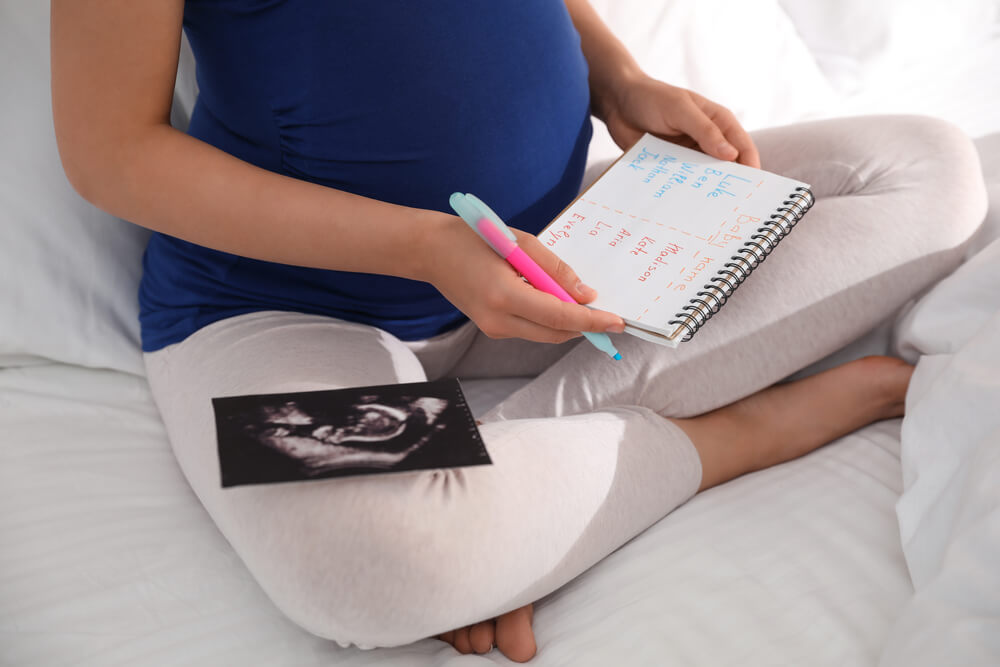 Pregnant woman writing a list of baby names